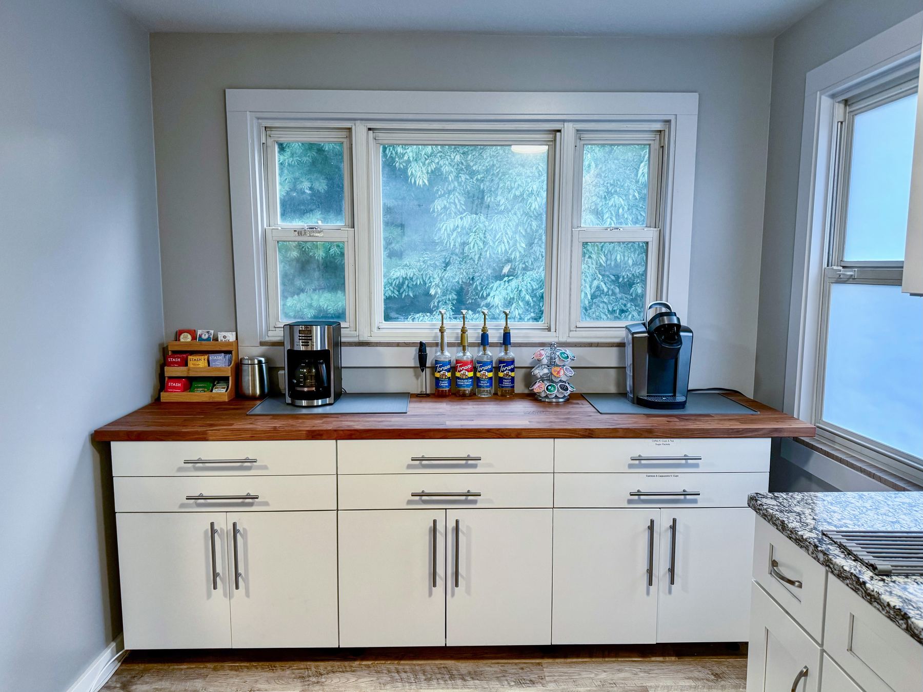 Coffee and tea station with a wood counter and window looking onto trees
