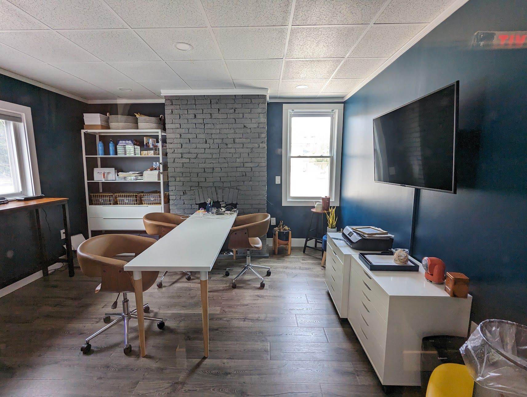 Conference room at PerryWorks with a white table, leather chairs, and a navy wall